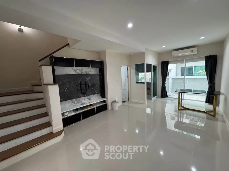 Spacious modern living room with sleek staircase and large windows