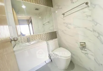 Modern bathroom with sleek design and marble tiles, featuring a toilet and sink.