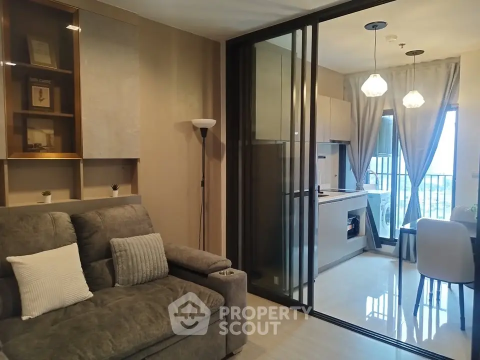 Modern living room with sliding glass doors leading to a stylish kitchen and dining area.