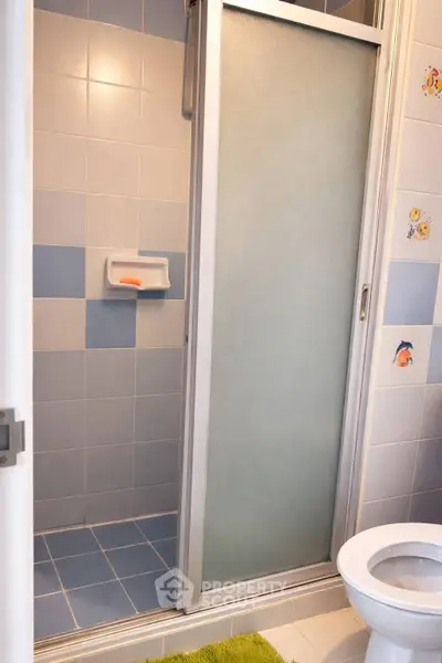 Charming bathroom with shower and toilet, featuring playful tile accents and modern fixtures.