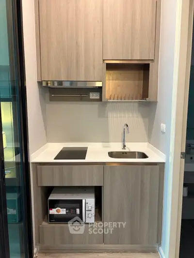 Modern compact kitchen with sleek cabinetry and built-in appliances in a stylish apartment.