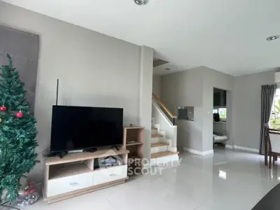 Modern living room with sleek TV setup and Christmas tree, bright and spacious interior