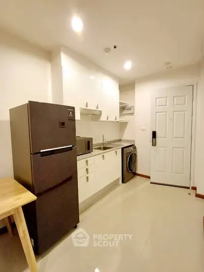 Modern kitchen with sleek appliances and ample storage in a cozy apartment.