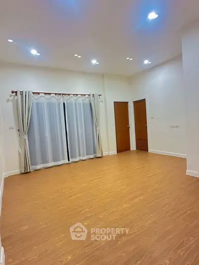 Spacious empty room with wooden flooring and modern lighting, ideal for customization.