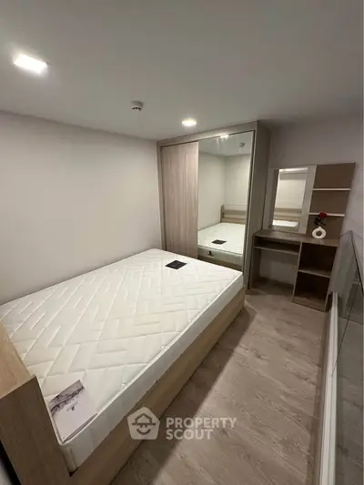 Modern minimalist bedroom with wooden flooring and mirrored wardrobe