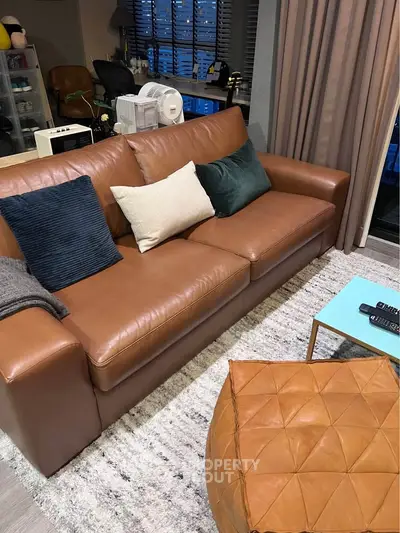 Stylish living room with leather sofa and modern decor in a cozy apartment setting.
