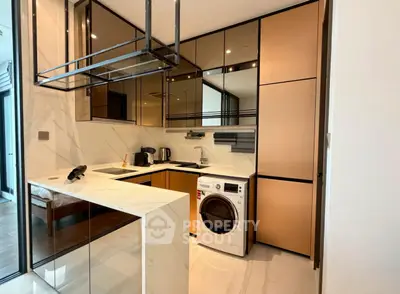 Modern kitchen with sleek cabinetry and built-in washing machine in luxury apartment.