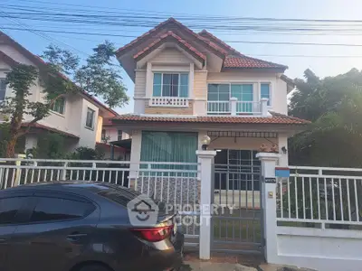 Charming two-story house with red-tiled roof and gated front yard in a serene neighborhood.
