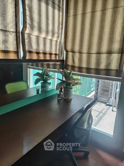 Cozy study room with desk, chair, and potted plants by a window with striped blinds.