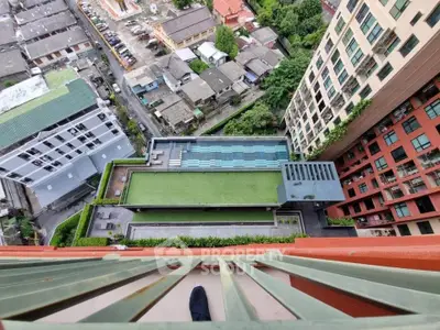 Stunning aerial view of modern apartment complex with rooftop pool and lush greenery.