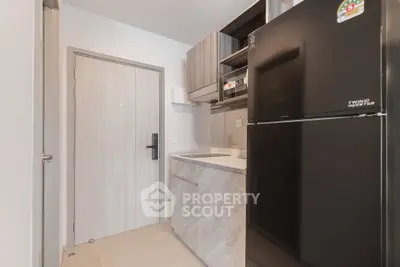 Modern kitchen with sleek cabinetry and black refrigerator in compact layout.