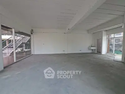 Spacious industrial-style open space with concrete floors and large windows.