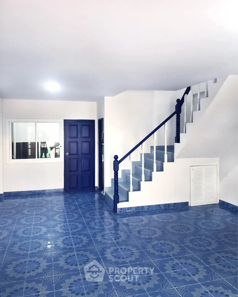 Charming interior with blue tiled floor and staircase, perfect for modern living.