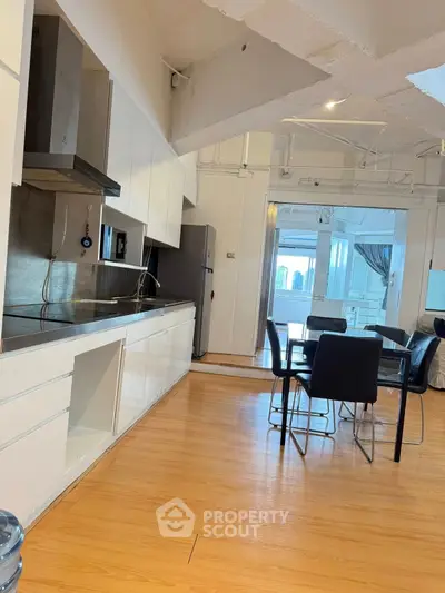 Modern open-layout kitchen with dining area and city view balcony.