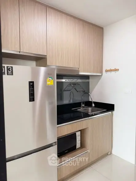 Modern compact kitchen with sleek wooden cabinets and stainless steel appliances.