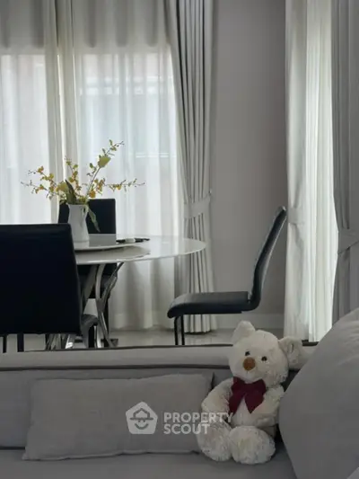 Elegant living room with plush teddy bear and stylish dining area
