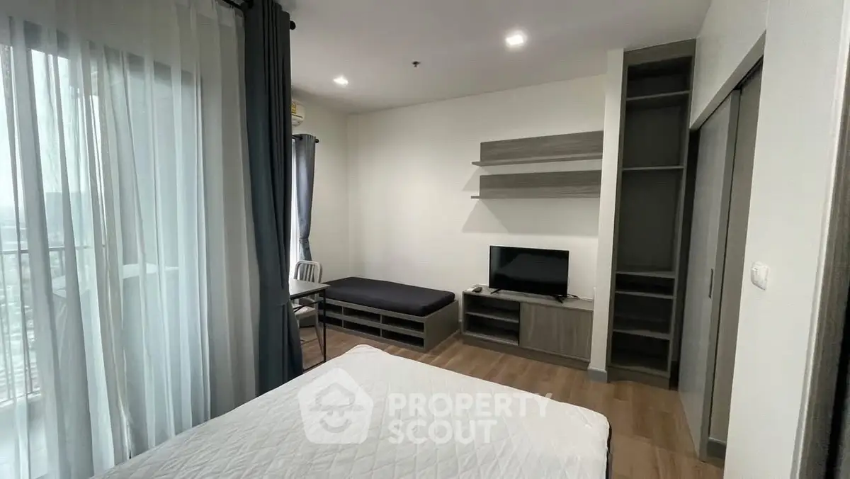 Modern bedroom with balcony view, featuring sleek furniture and ample natural light.