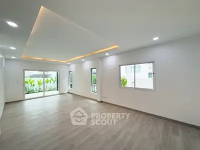 Spacious modern living room with large windows and elegant ceiling lighting.