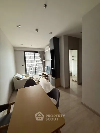 Modern living room with stylish furniture and large window offering natural light in urban apartment.