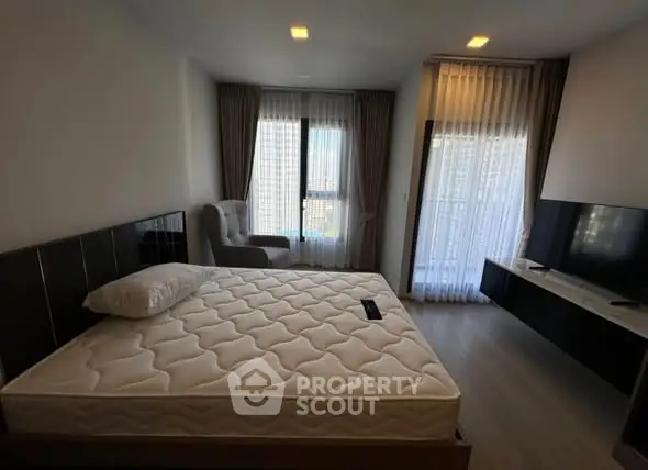 Modern bedroom with large windows and natural light, featuring a comfortable bed and sleek decor.