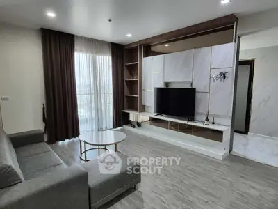 Modern living room with sleek furniture and large window offering natural light.