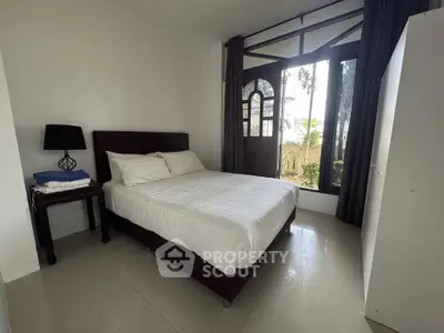 Cozy bedroom with large window and modern furnishings in a serene setting.