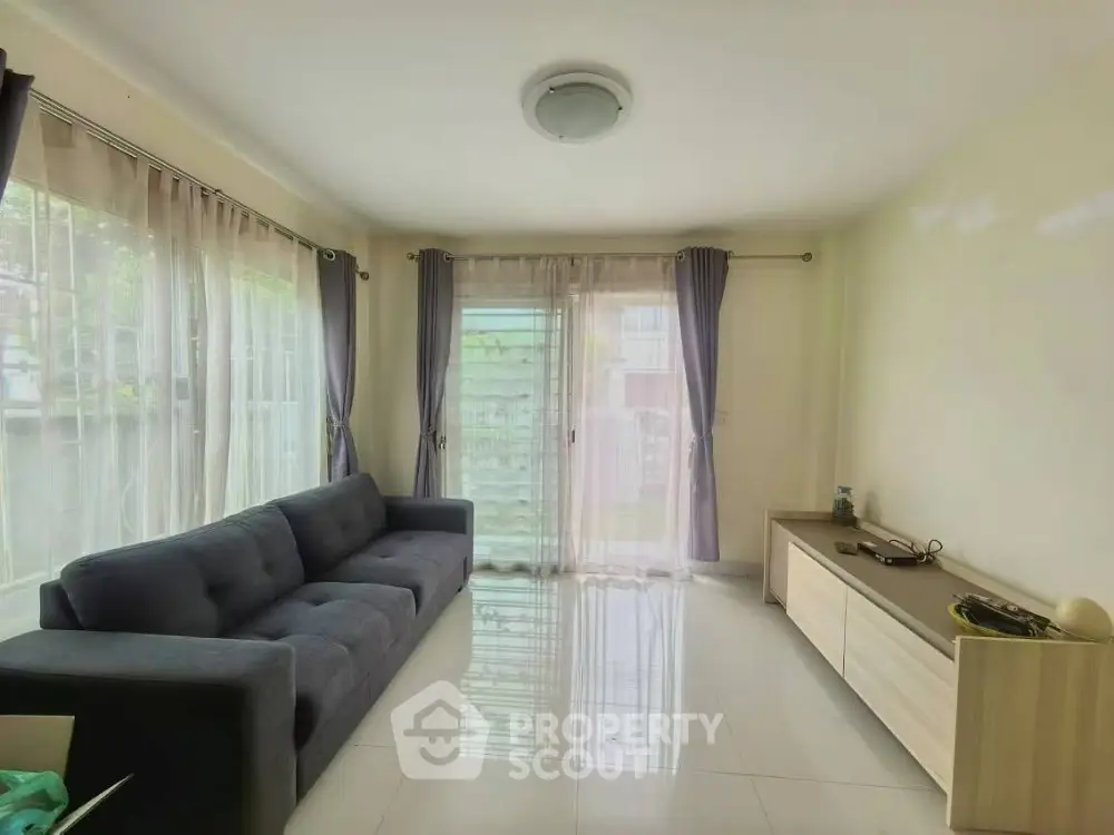 Spacious living room with modern sofa and large windows offering natural light