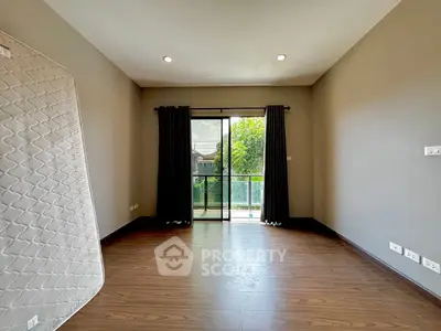 Spacious empty bedroom with hardwood floors and large window overlooking greenery.