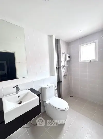 Modern bathroom with sleek fixtures and natural light, featuring a spacious shower area and contemporary design.
