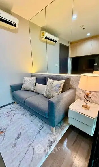 Modern living room with stylish sofa, elegant lighting, and mirrored wall enhancing space.