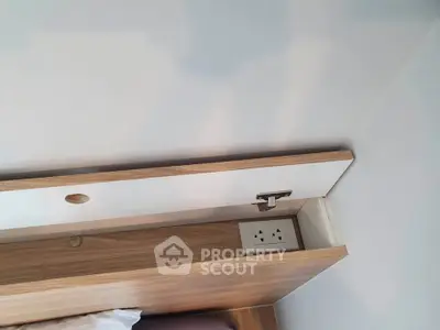 Modern bedroom with built-in wooden headboard featuring convenient power outlet.