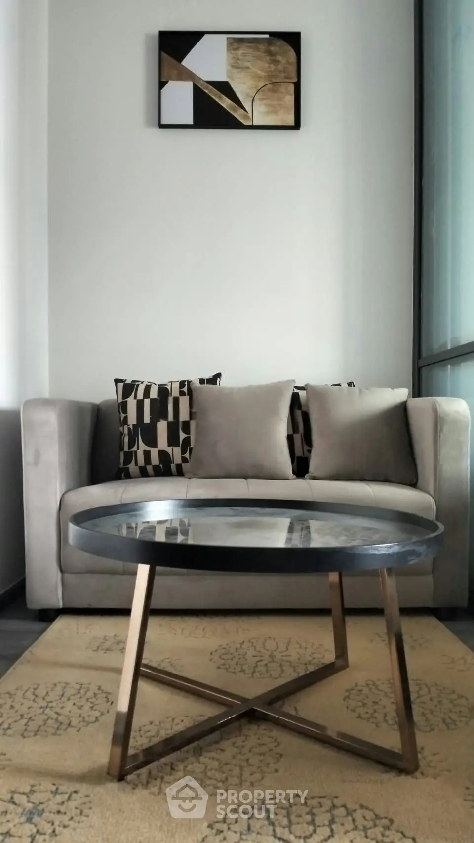 Modern living room with stylish sofa, geometric cushions, and elegant coffee table on patterned rug.