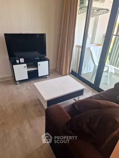 Modern living room with sleek TV stand and cozy sofa, leading to a bright balcony.