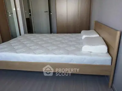 Spacious bedroom with modern wooden bed frame and comfortable mattress.