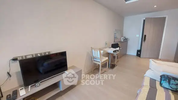 Modern bedroom with TV and workspace, featuring minimalist decor and neutral tones.