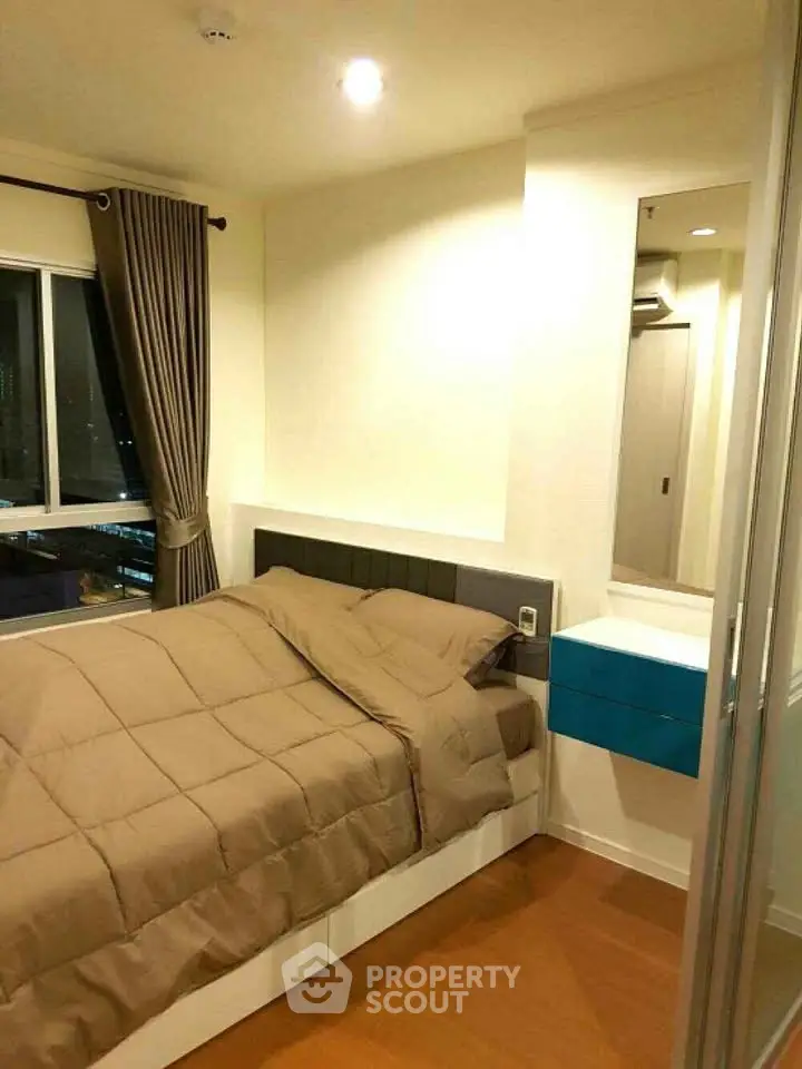 Cozy bedroom with modern decor and large window offering city views.