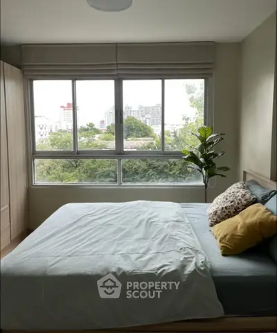 Cozy bedroom with large window and city view, featuring modern decor and lush greenery outside.