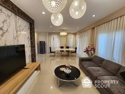 Luxurious spacious living room with elegant marble wall accents, modern chandeliers, and plush seating, perfect for upscale living.