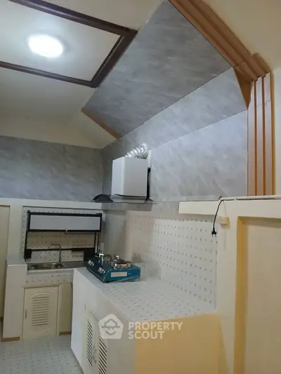 Compact kitchen with gas stove and modern cabinetry in cozy apartment
