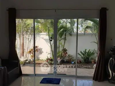 Spacious living room with sliding glass doors opening to lush garden view.