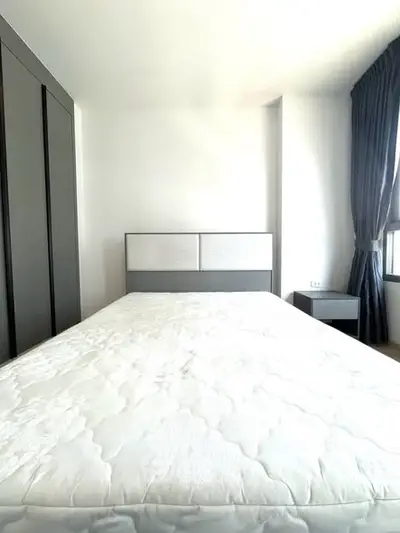 Spacious bedroom with modern design and ample natural light, featuring a comfortable bed and stylish wardrobe.