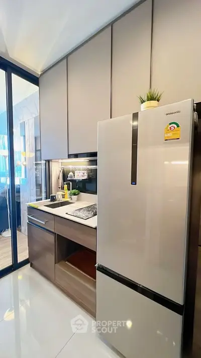 Modern kitchen with sleek cabinetry and stainless steel fridge in a stylish apartment.