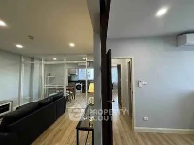 Modern apartment interior with open living room and study area, featuring sleek design and natural lighting.