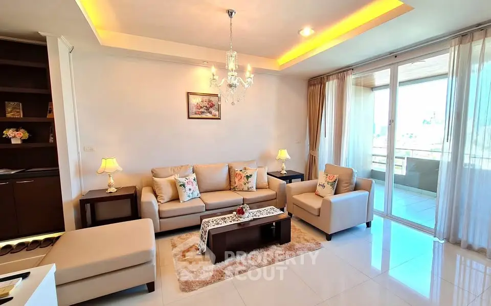 Elegant living room with chandelier and balcony access, featuring cozy seating and modern decor.