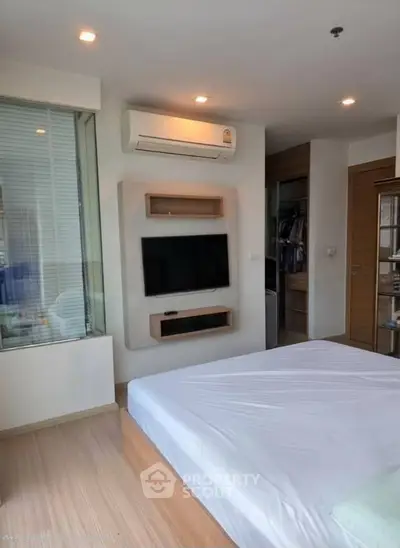 Modern bedroom with built-in TV and air conditioning, featuring a sleek design and ample natural light.
