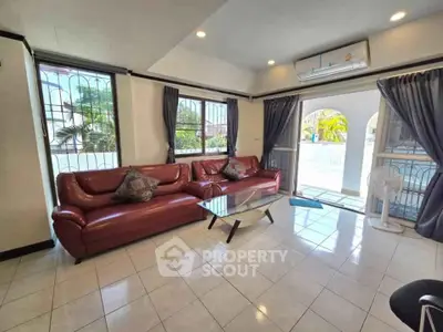 Spacious living room with red leather sofa and large windows for natural light.