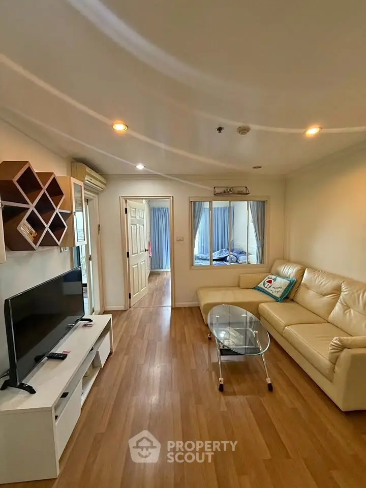 Spacious living room with modern decor and wooden flooring, featuring a cozy sofa and entertainment center.