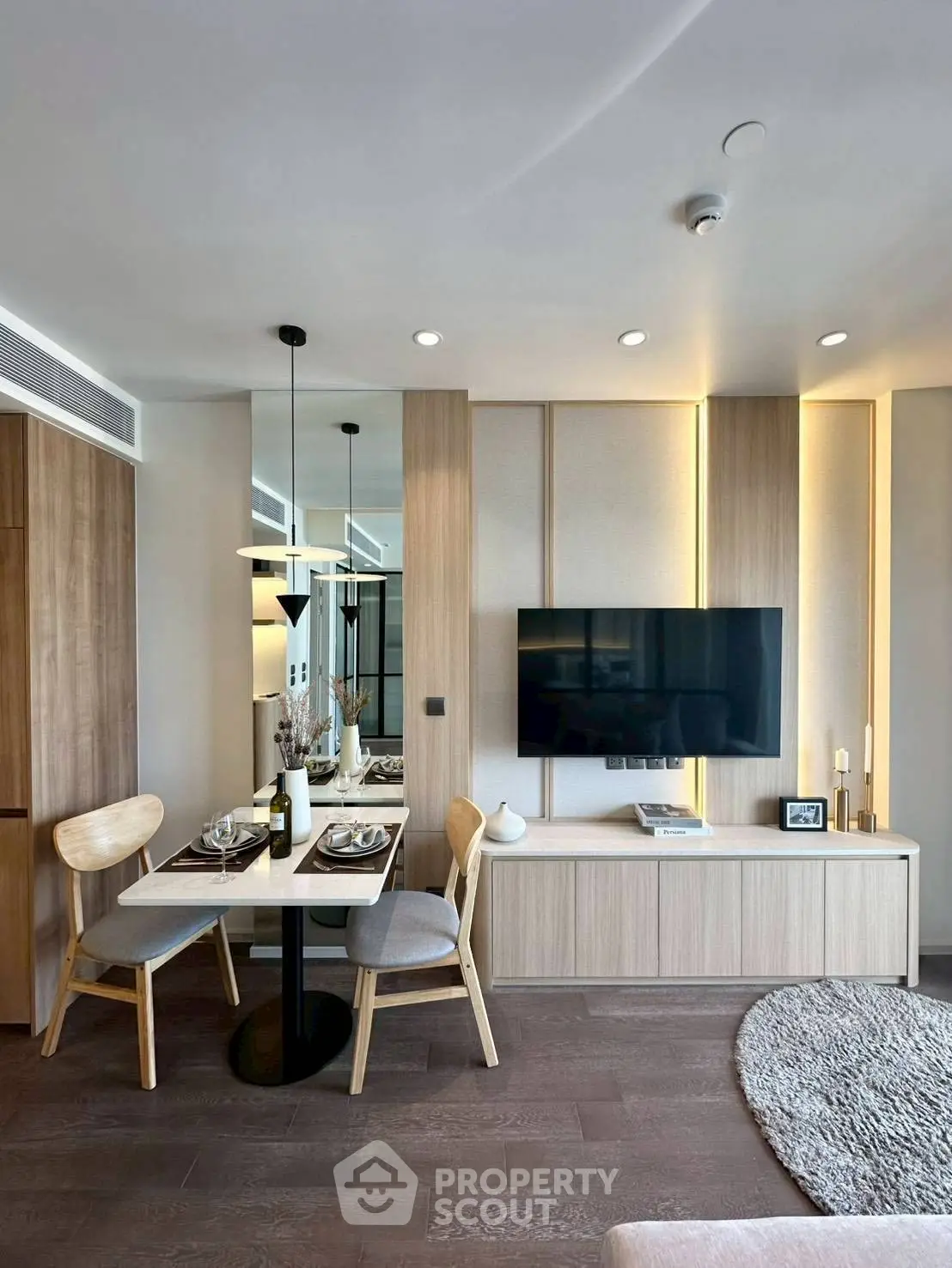 Modern living room with stylish decor, wall-mounted TV, and elegant dining area in a contemporary apartment.