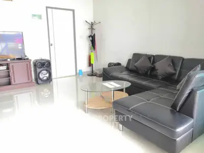 Modern living room with sleek black leather sofa and glass coffee table, perfect for stylish urban living.