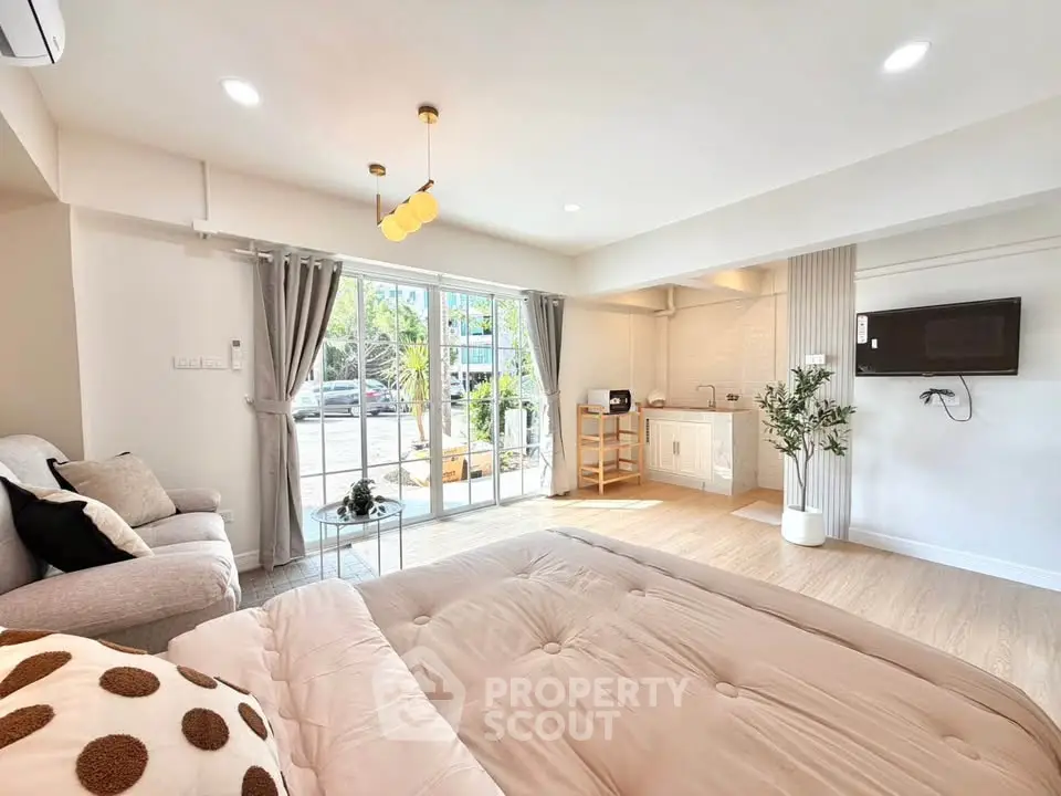 Spacious modern studio with open layout and large windows offering natural light and garden view.